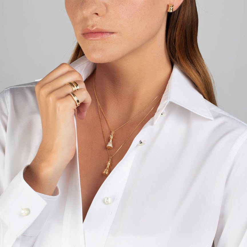 Woman wearing a white shirt with gold jewelry on a gray background