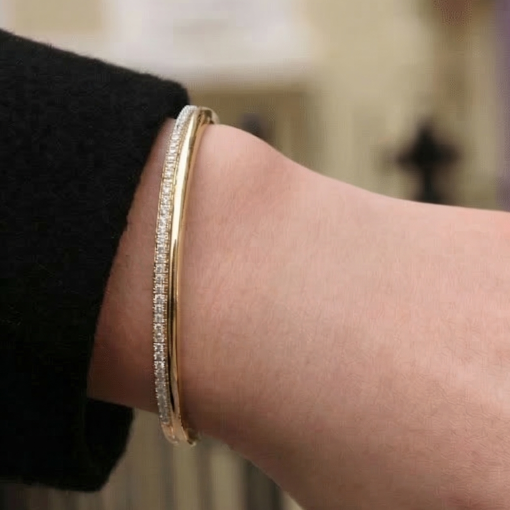 yellow gold white diamond double row bangle bracelet on a models hand wearing a black jacket