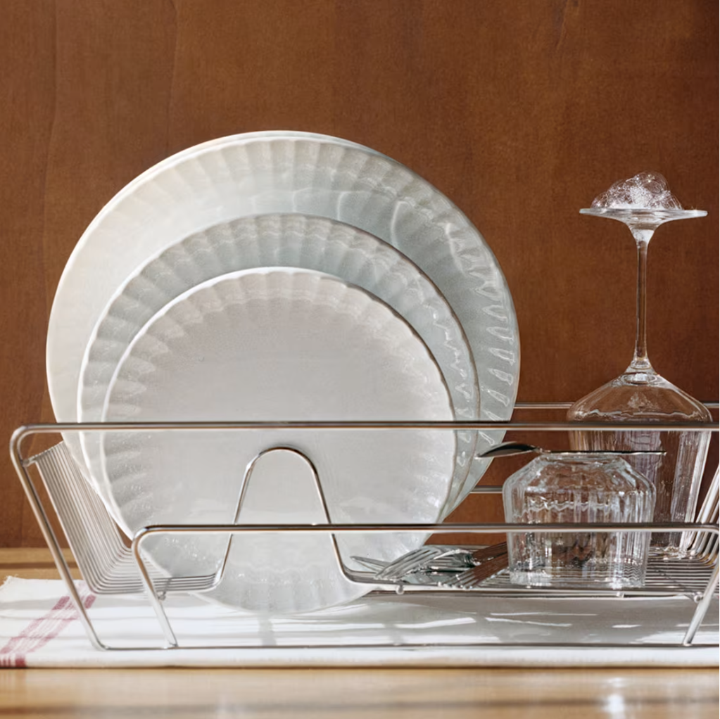 Stack of white plates on a dish rack with a brown background