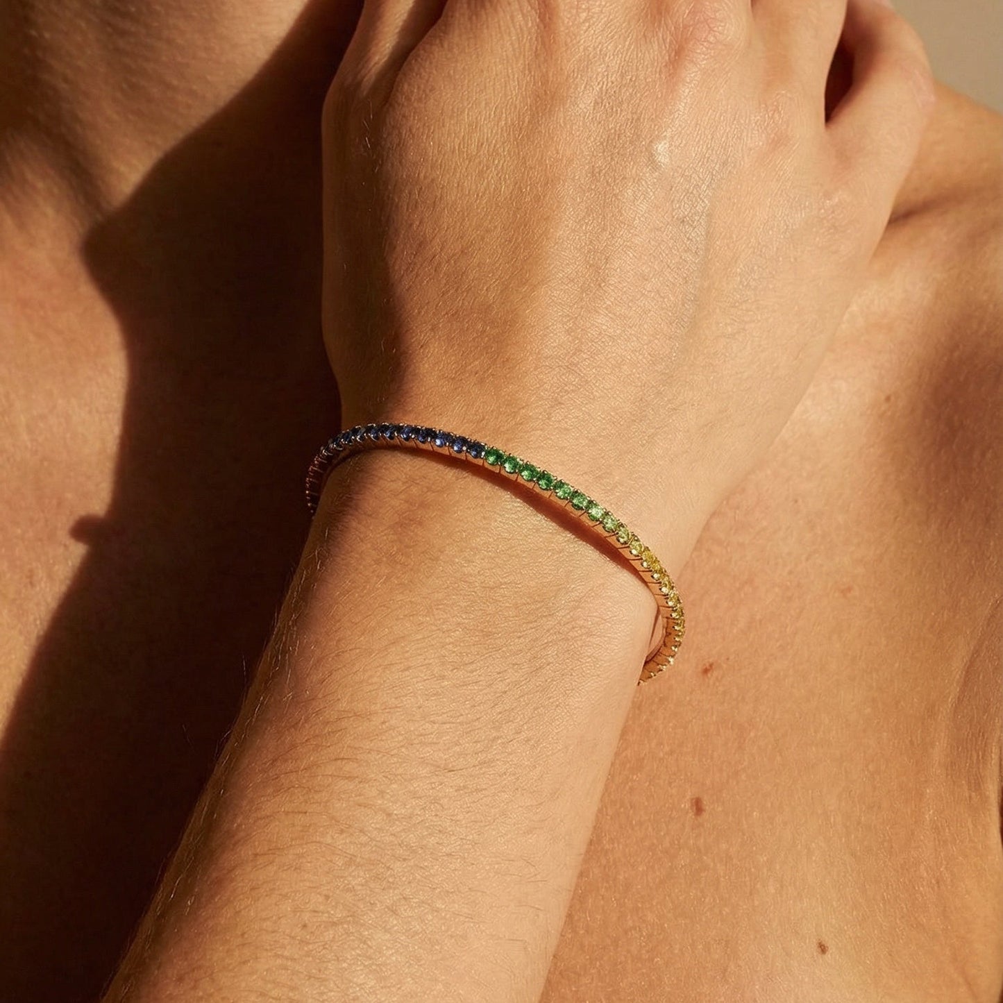 rainbow sapphire tennis bracelet close up image of the models hand