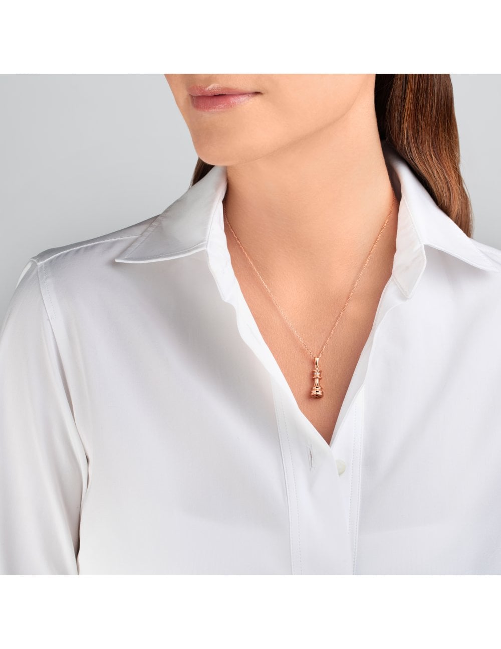 Model wearing white shirt and a chess queen rose gold and diamond necklace