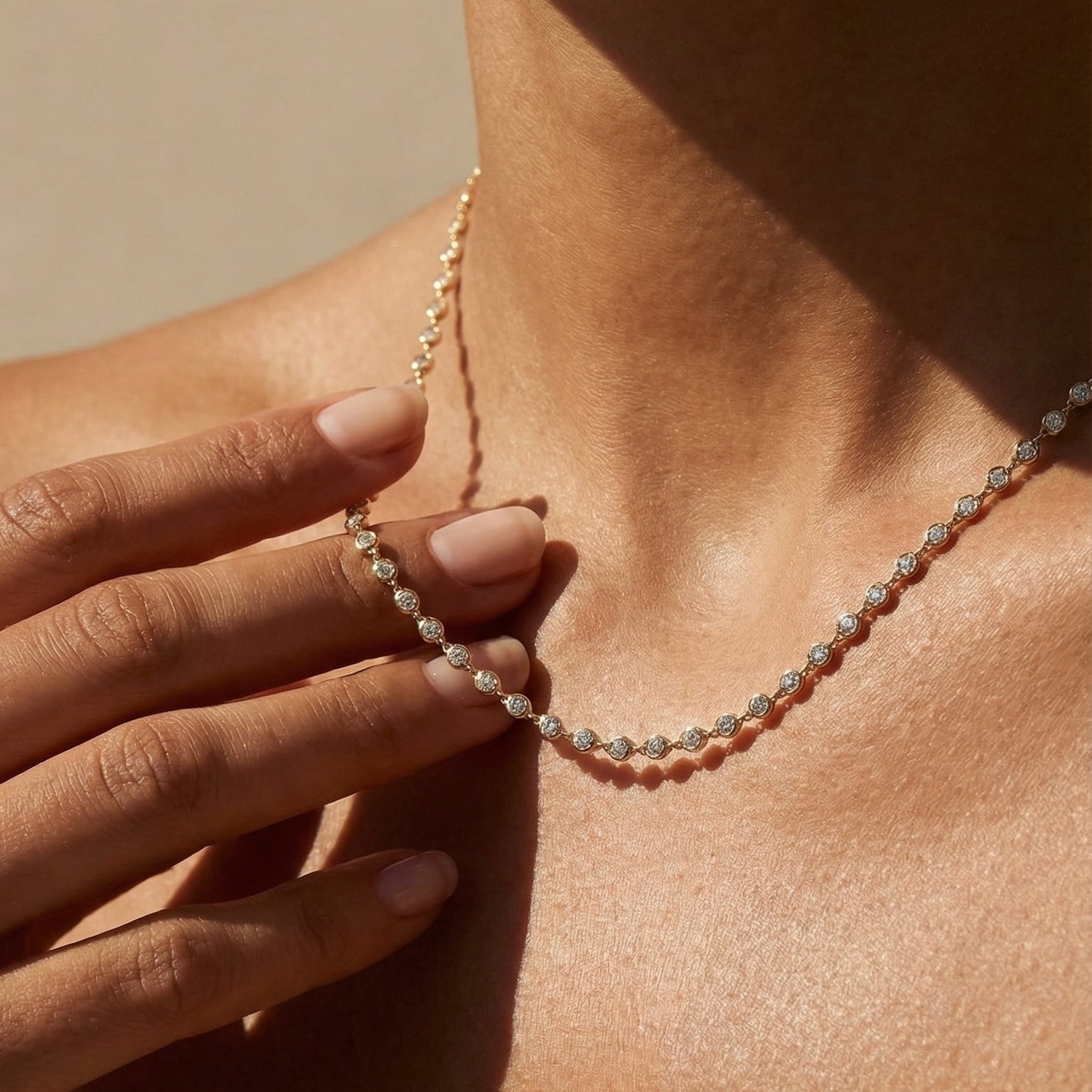 Close-up of a person wearing a delicate necklace with a neutral background