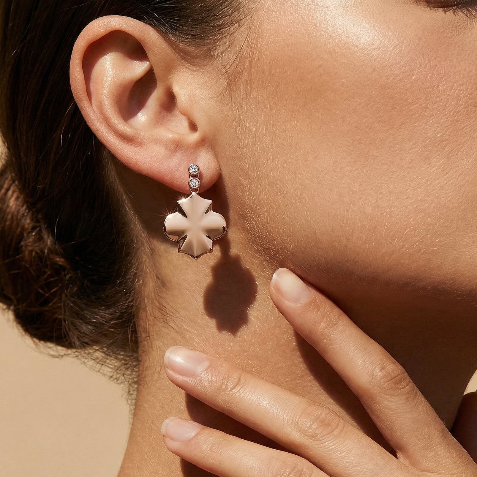 rose gold geometrical shape drop earrings with white diamonds close up image on a models ear 
