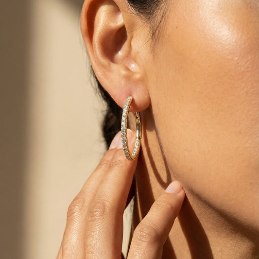 Close-up of a person wearing a diamond hoop earring with a soft background
