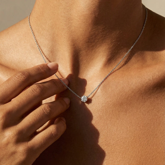 Close-up of a person wearing a necklace with a hand touching the neck