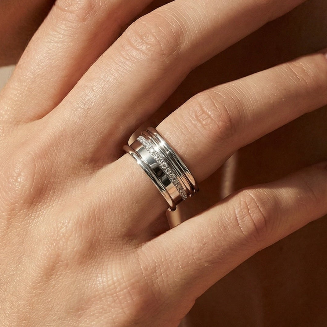 Close-up of a hand wearing a ring on a neutral background