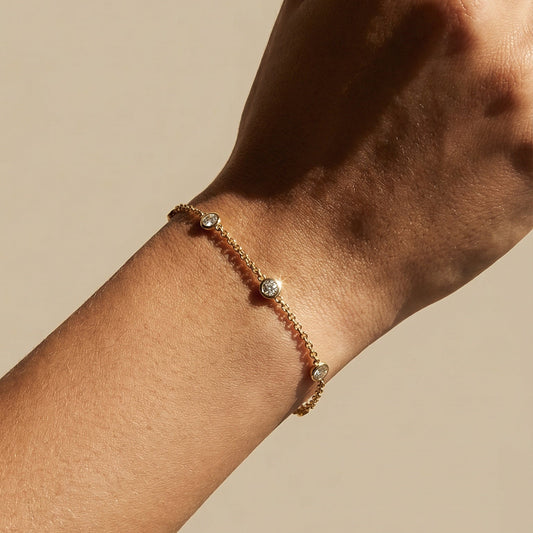 yellow gold three diamond chain bracelet close up on a models hand