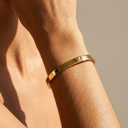 flat profile yellow gold bangle on a model hand 