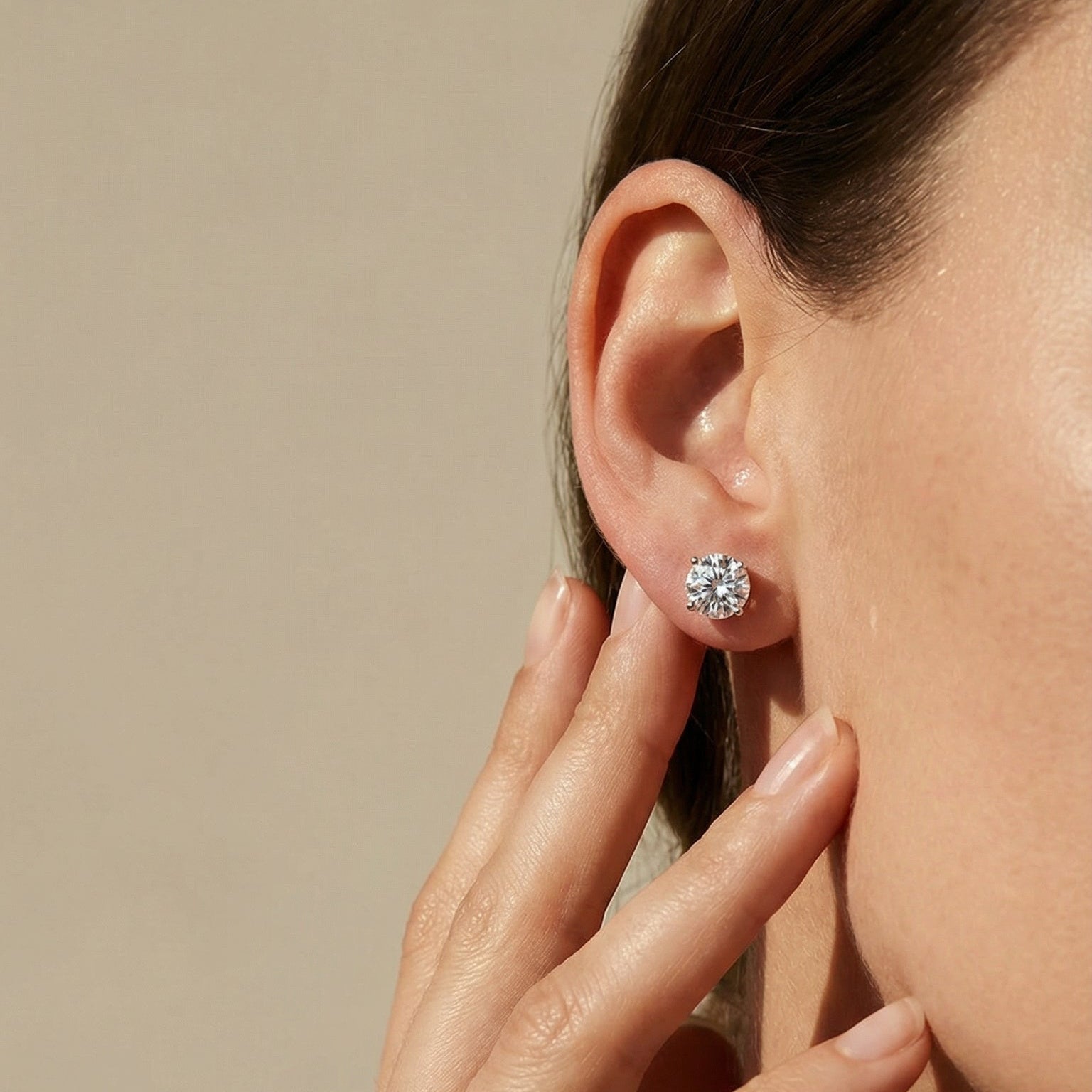 Close-up of a person wearing a diamond earring with a neutral background