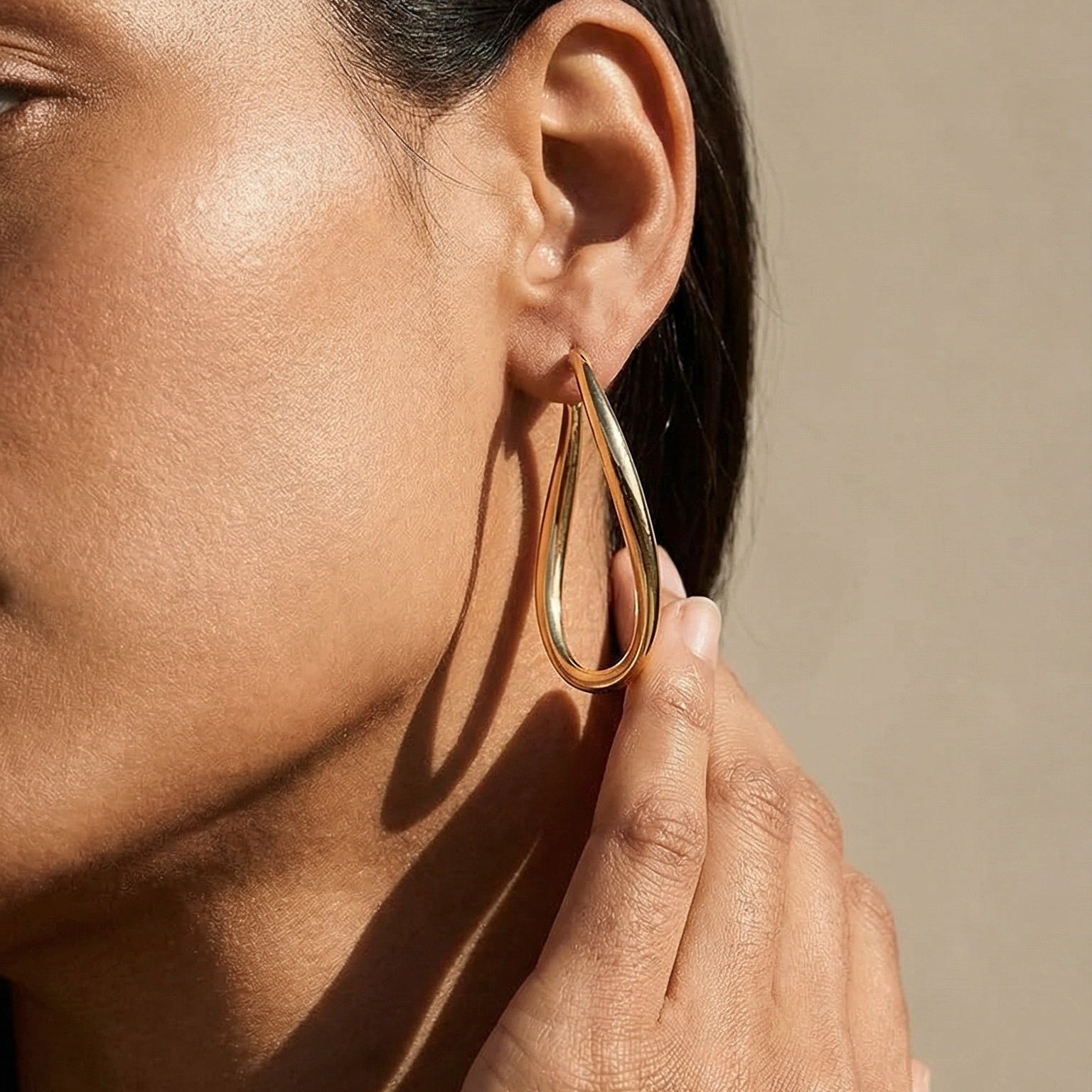 yellow gold twisted hoop earrings on a model 