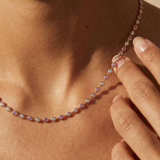 Necklace with multicolored beads worn by a person, with a hand touching the necklace.