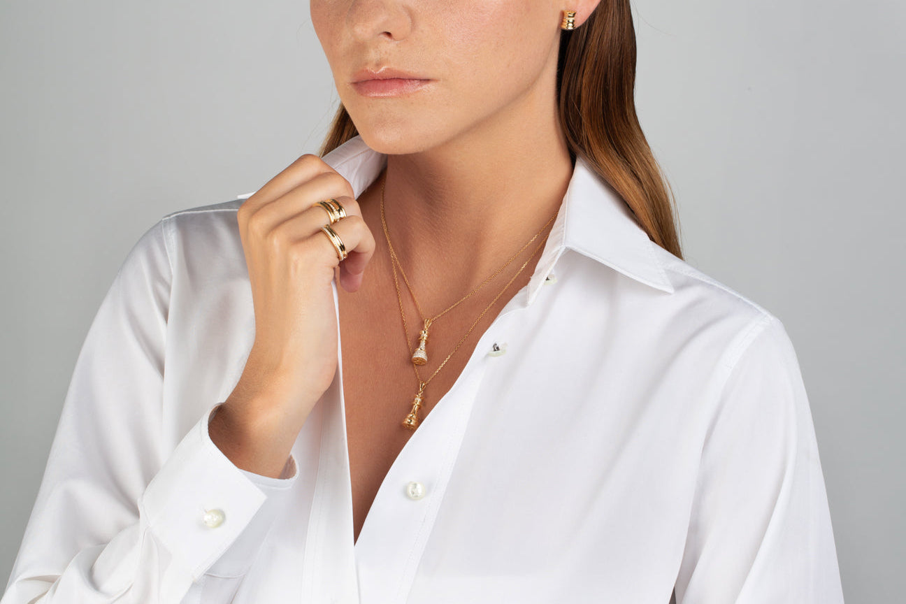 Woman wearing a white shirt with gold jewelry on a gray background