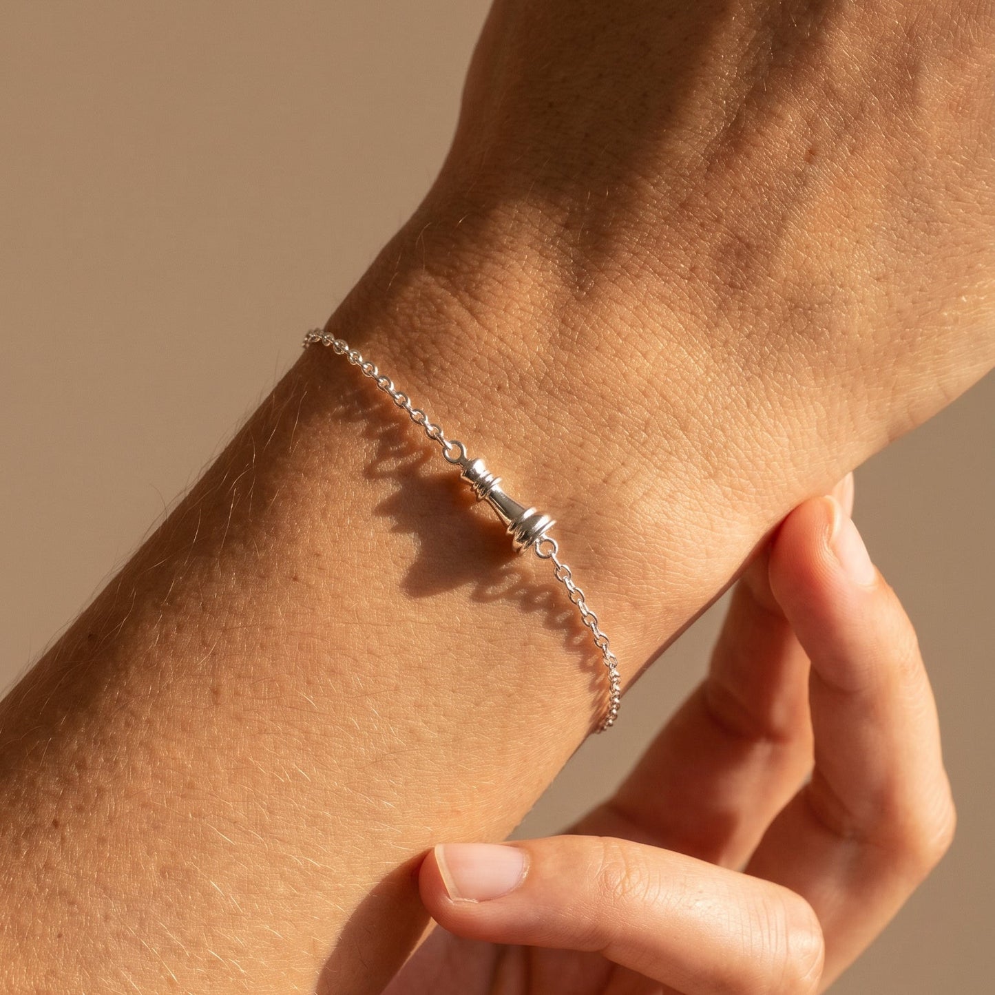 Ksenia Mirella Jewellery White gold chain queen bracelet worn on a models hand on a neutral background 