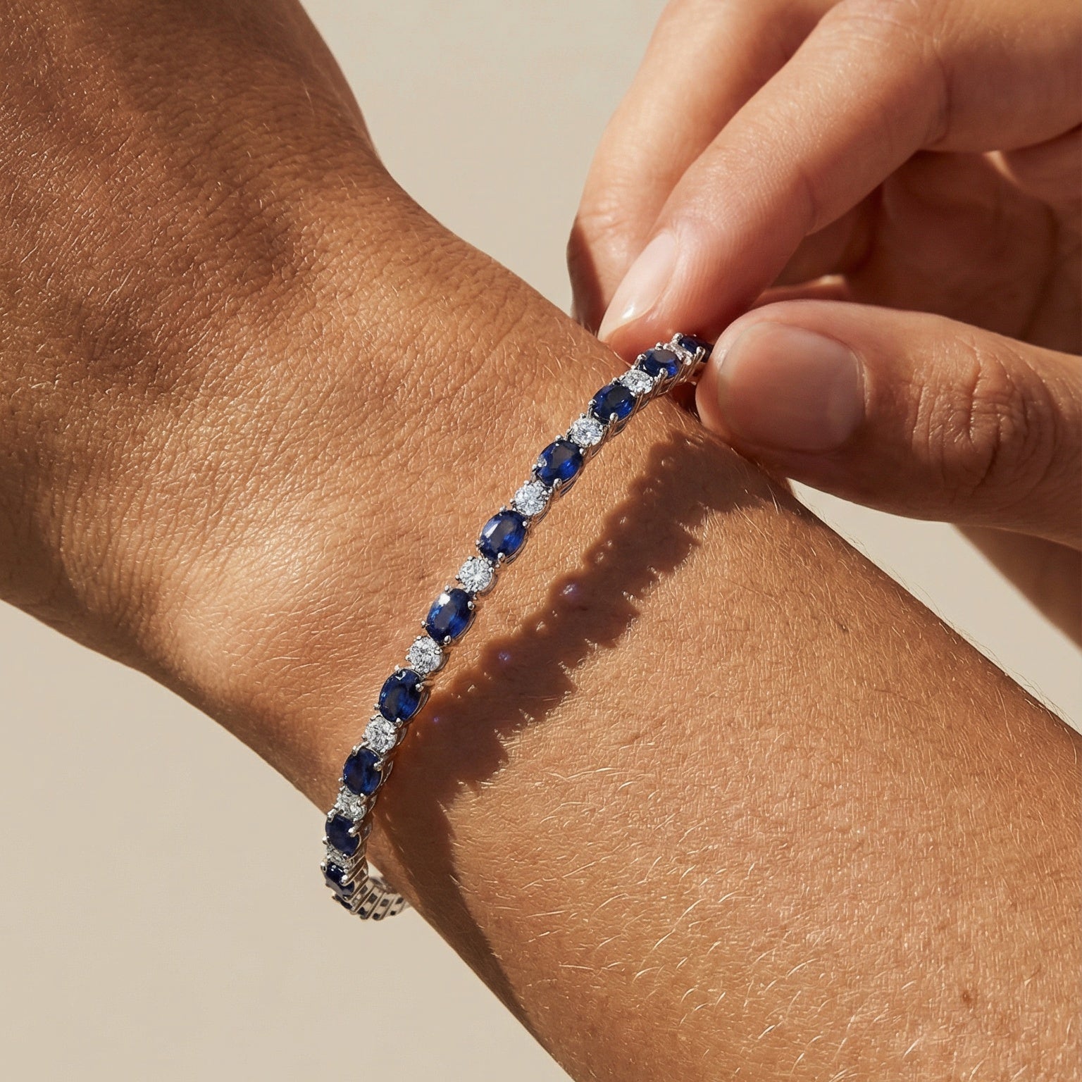 Person wearing a blue beaded bracelet on a beige background