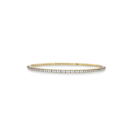 A delicate gold bangle bracelet with a row of small clear stones along the front, displayed against a solid white background.