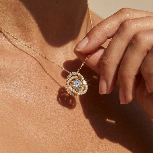 Close-up of a gold necklace with a heart-shaped pendant worn by a person.