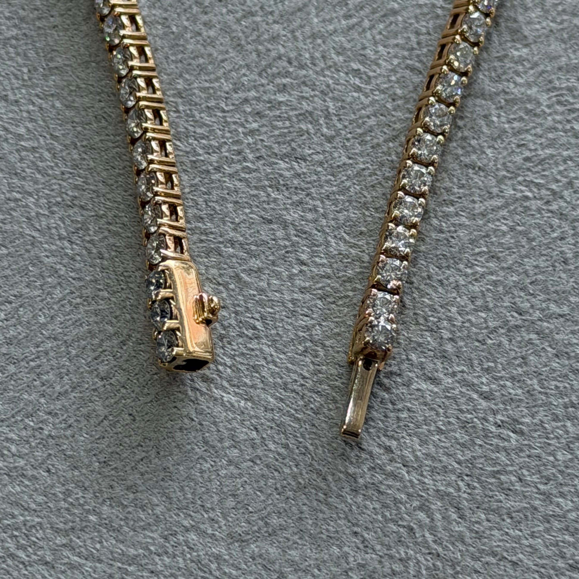 Two gold bracelets with diamond accents on a gray surface