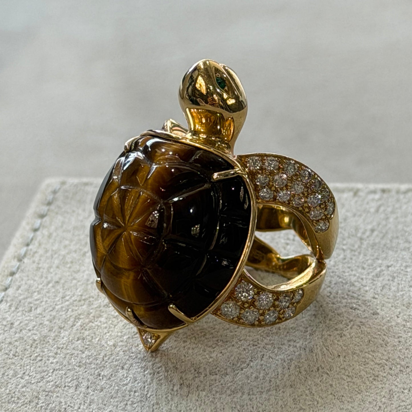 Gold ring with a large brown gemstone on a textured beige surface