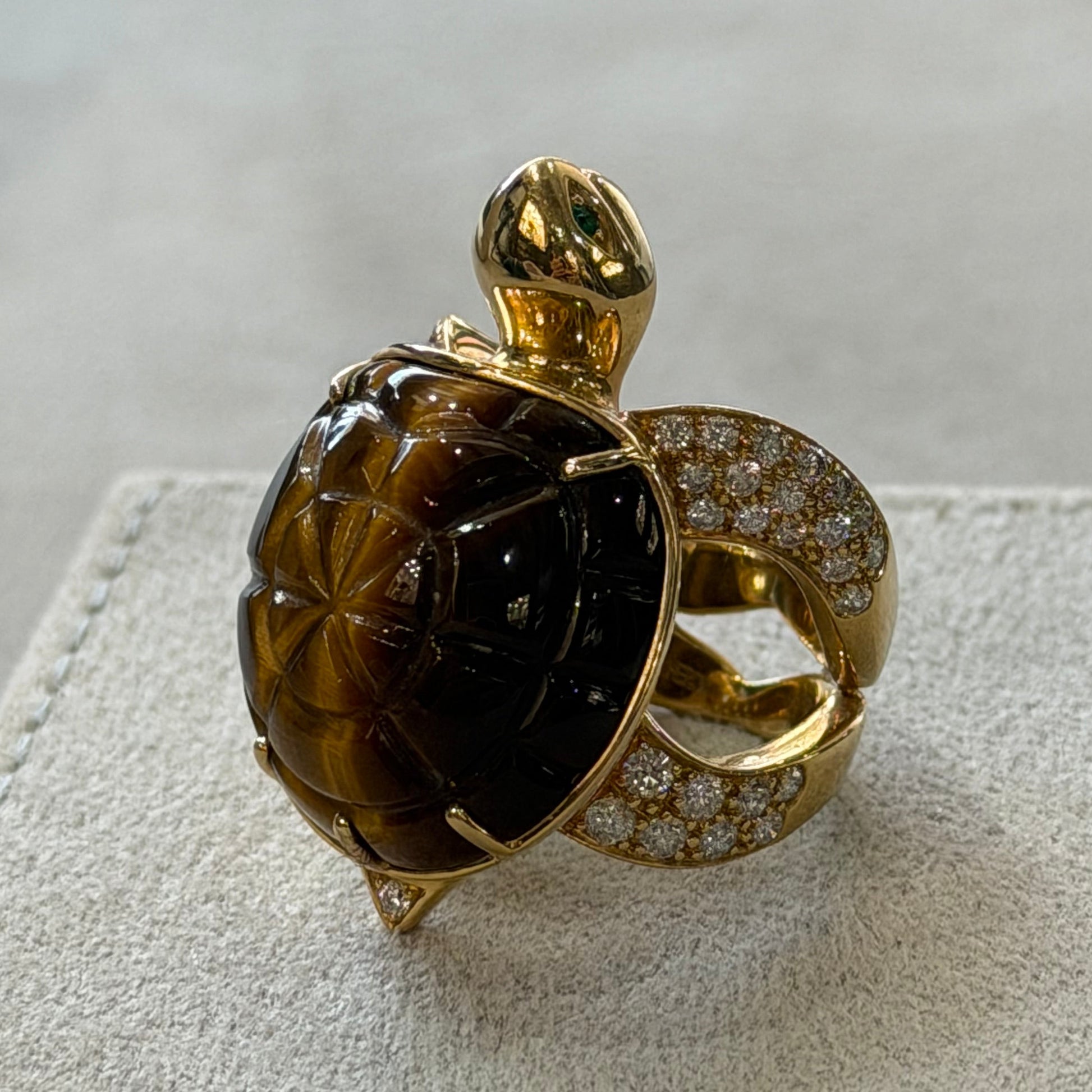 Gold ring with a large brown gemstone on a textured beige surface