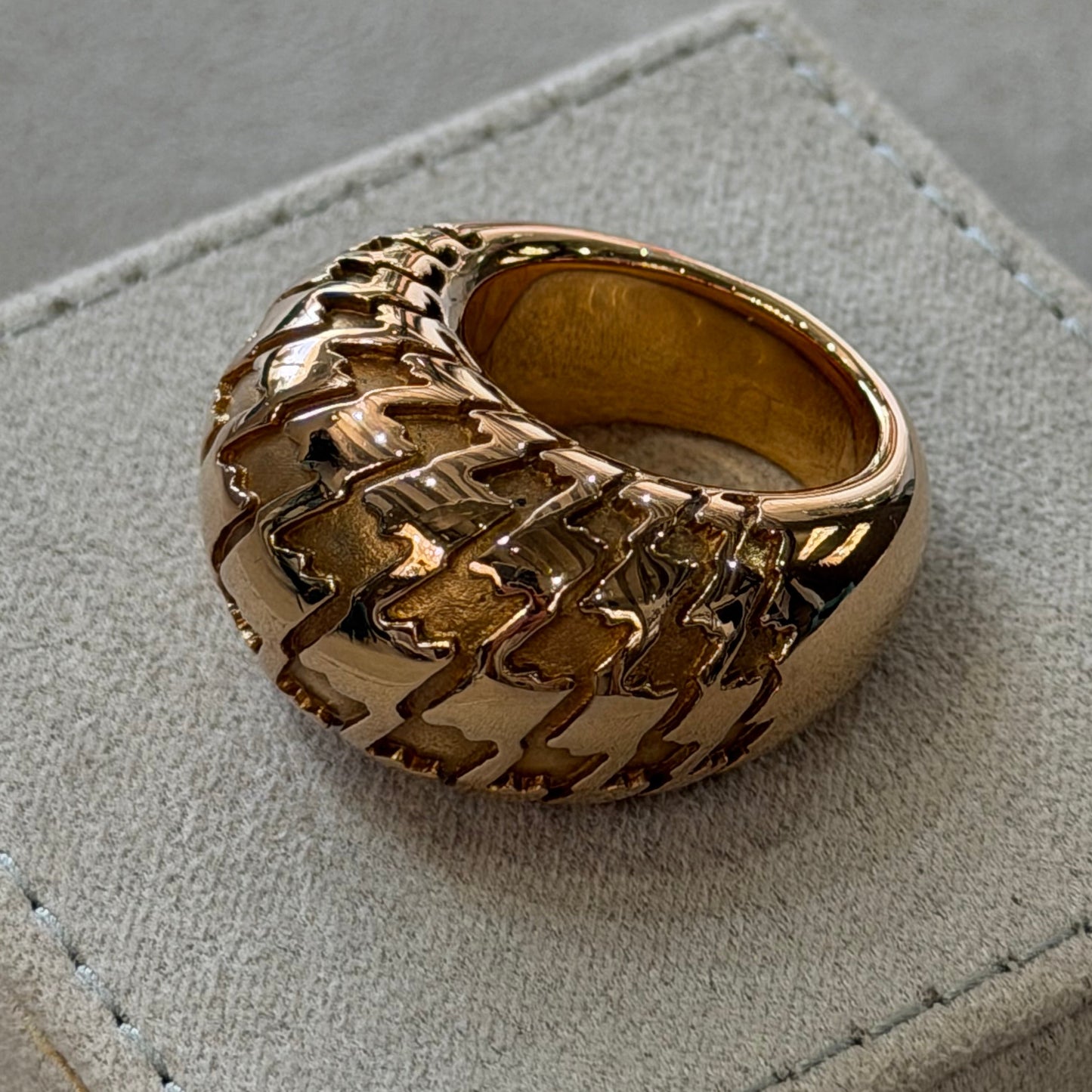 Gold ring with a textured band on a gray surface