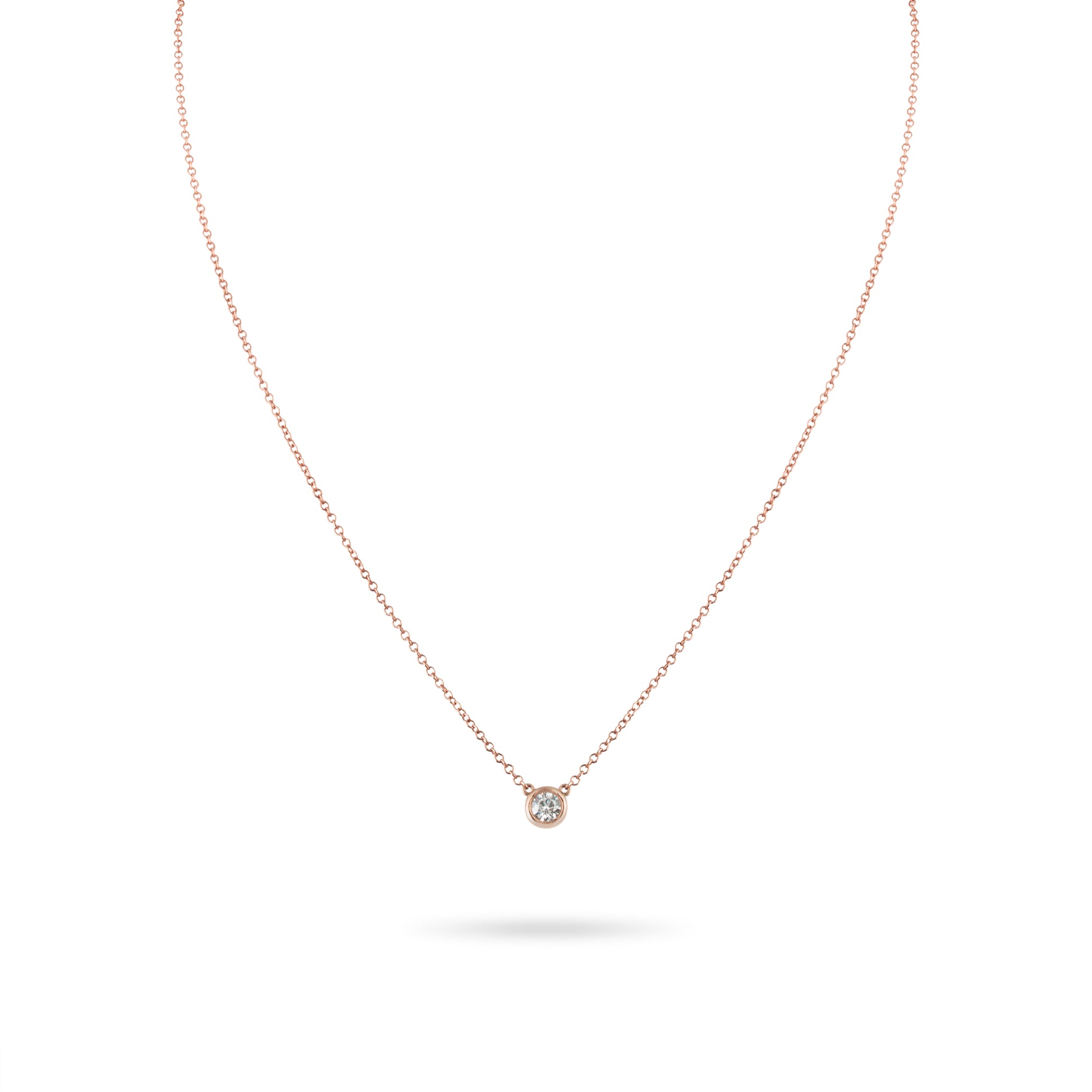 Rose gold necklace with a small diamond pendant on a white background