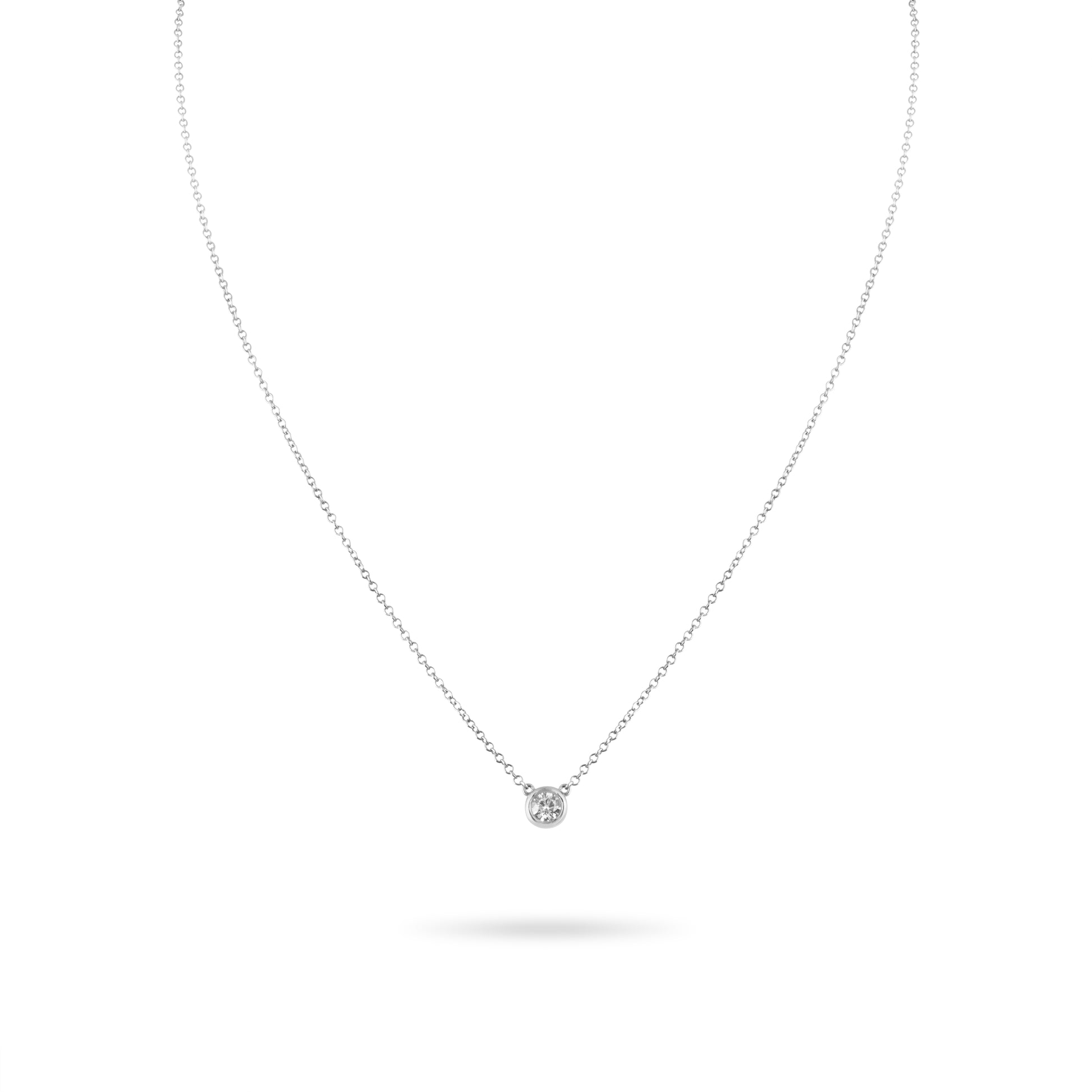 Delicate silver necklace with a small round pendant on a white background