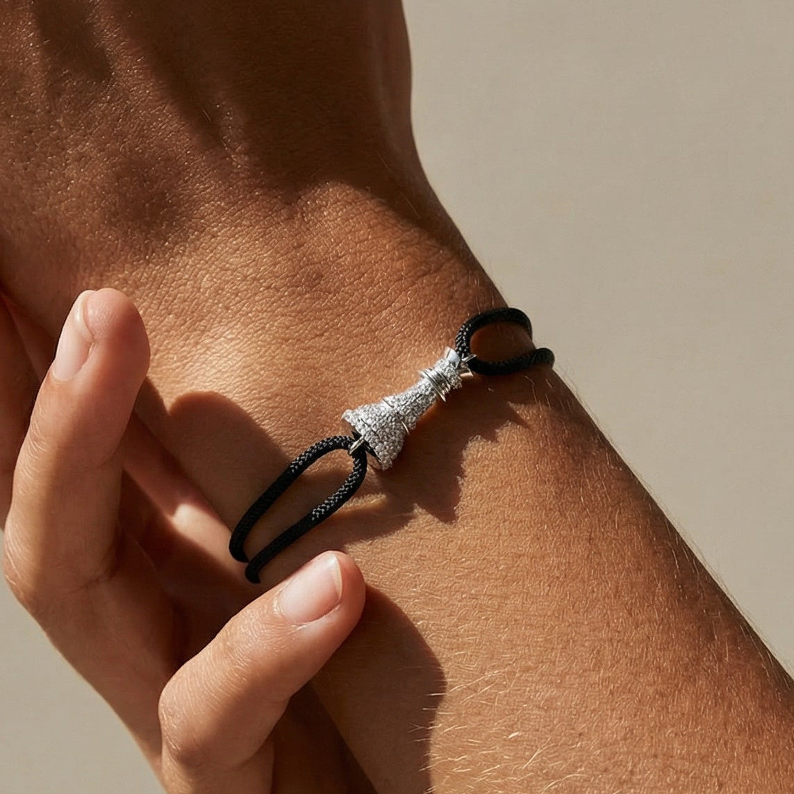 white gold white diamond paave cord bracelet on a models hand featuring a chess queen 