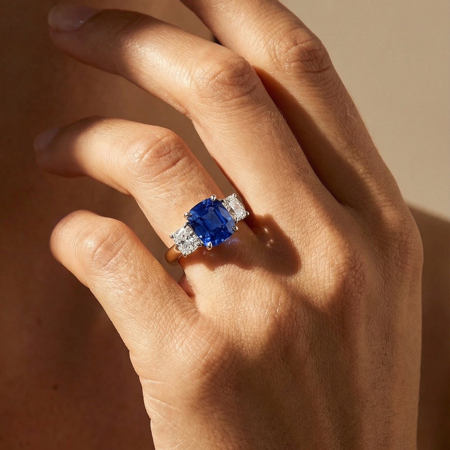 close up image of the models hand wearing a blue sapphire diamond ring in yellow gold 