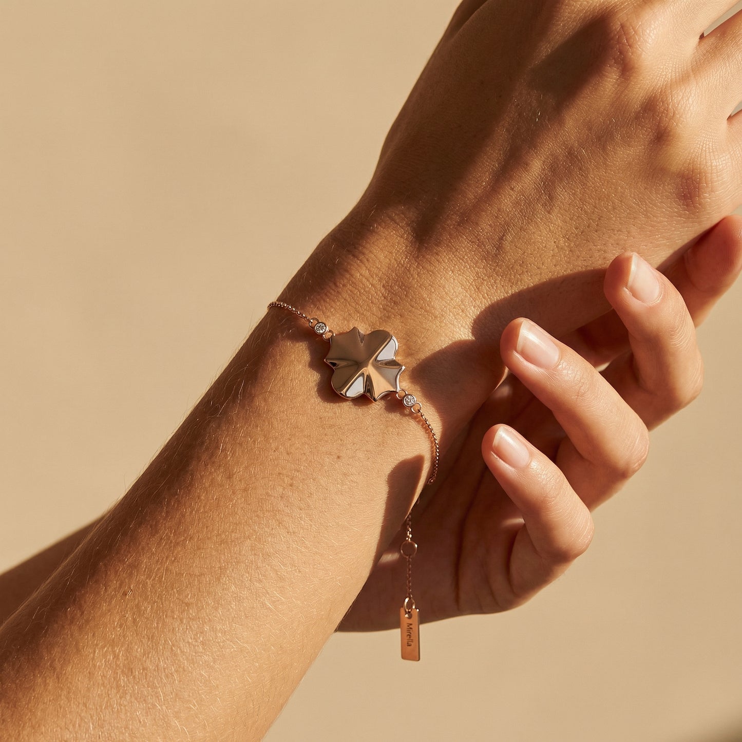 rose gold geometrical shape chain bracelet close up image of a models hand on a neutral background 