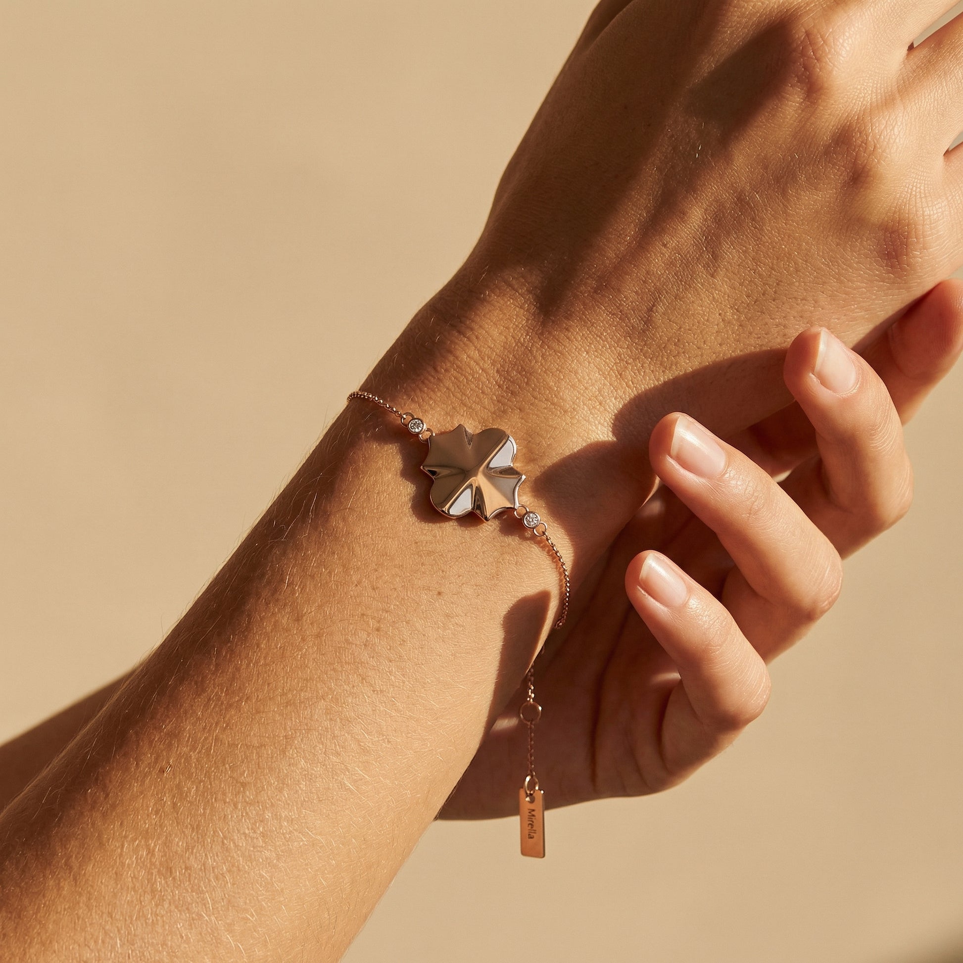 rose gold geometrical shape chain bracelet close up image of a models hand on a neutral background 