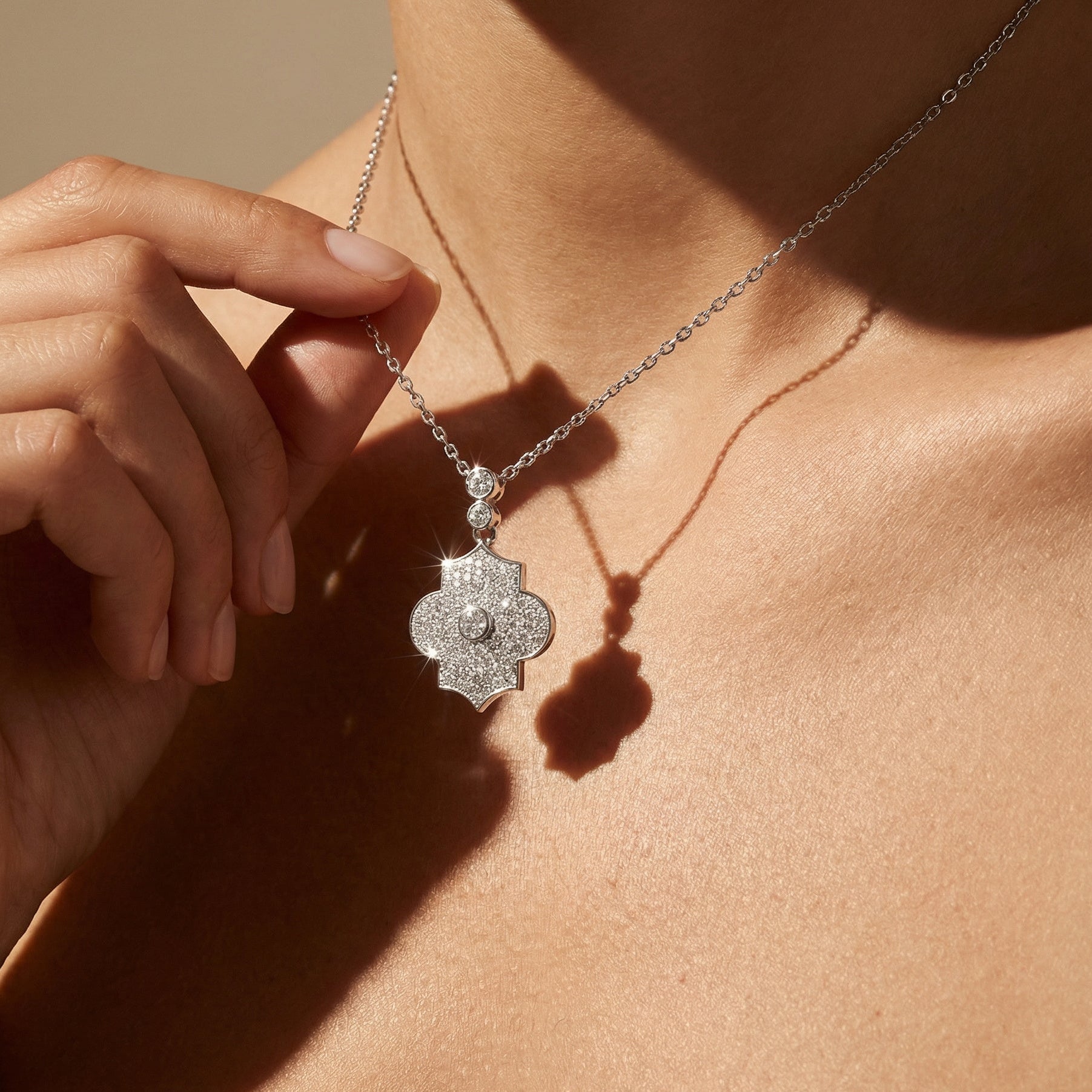 Close-up of a silver necklace with a pendant worn by a person.