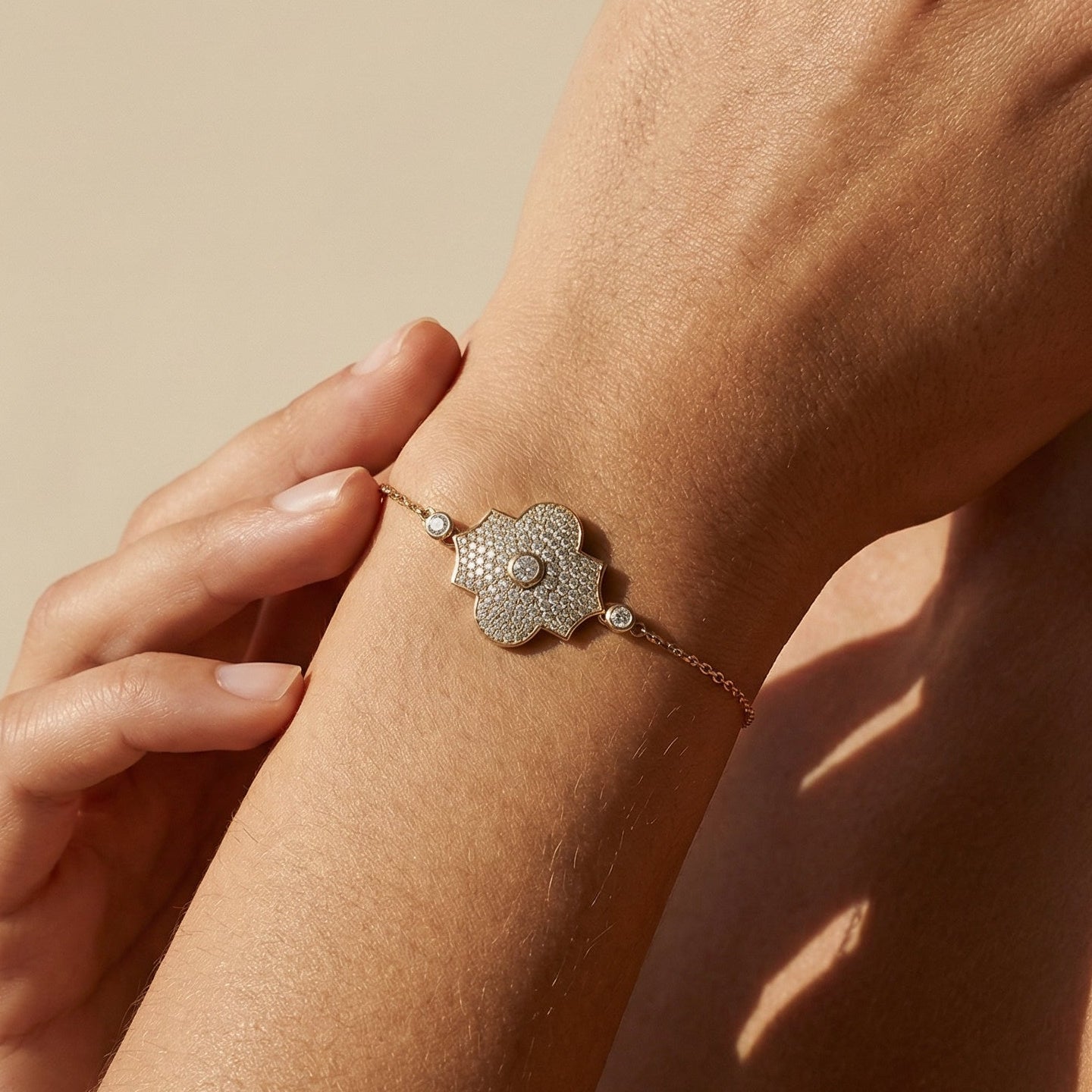 Close-up of a hand wearing a delicate bracelet on a beige background
