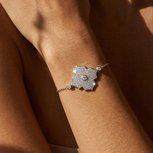 white gold white diamond bracelet with a geometric design on a wrist against a brown background