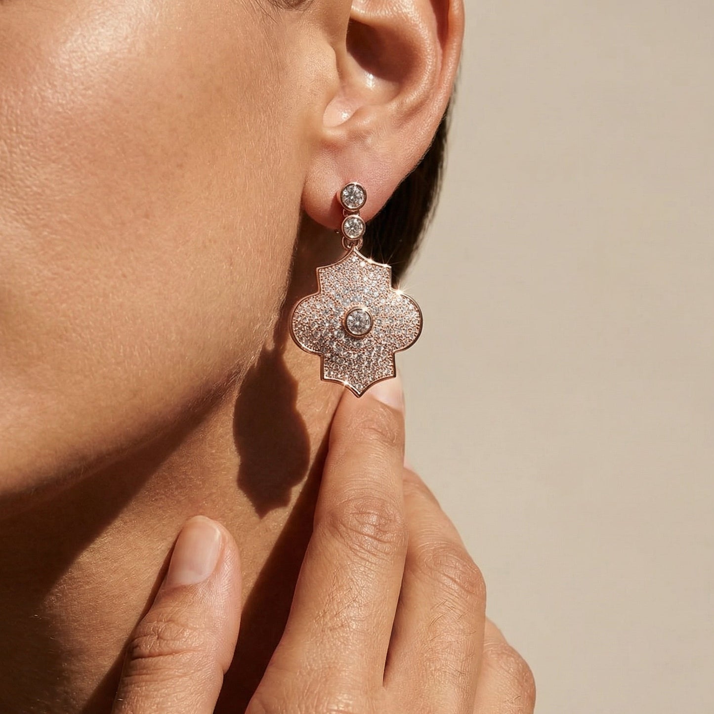 Close-up of a person wearing a sparkling earring with a neutral background