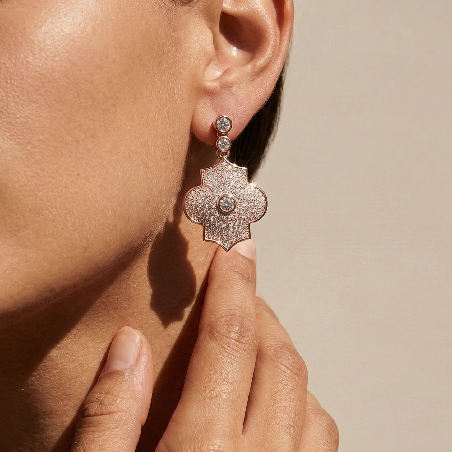 Close-up of a person wearing a sparkling earring with a neutral background