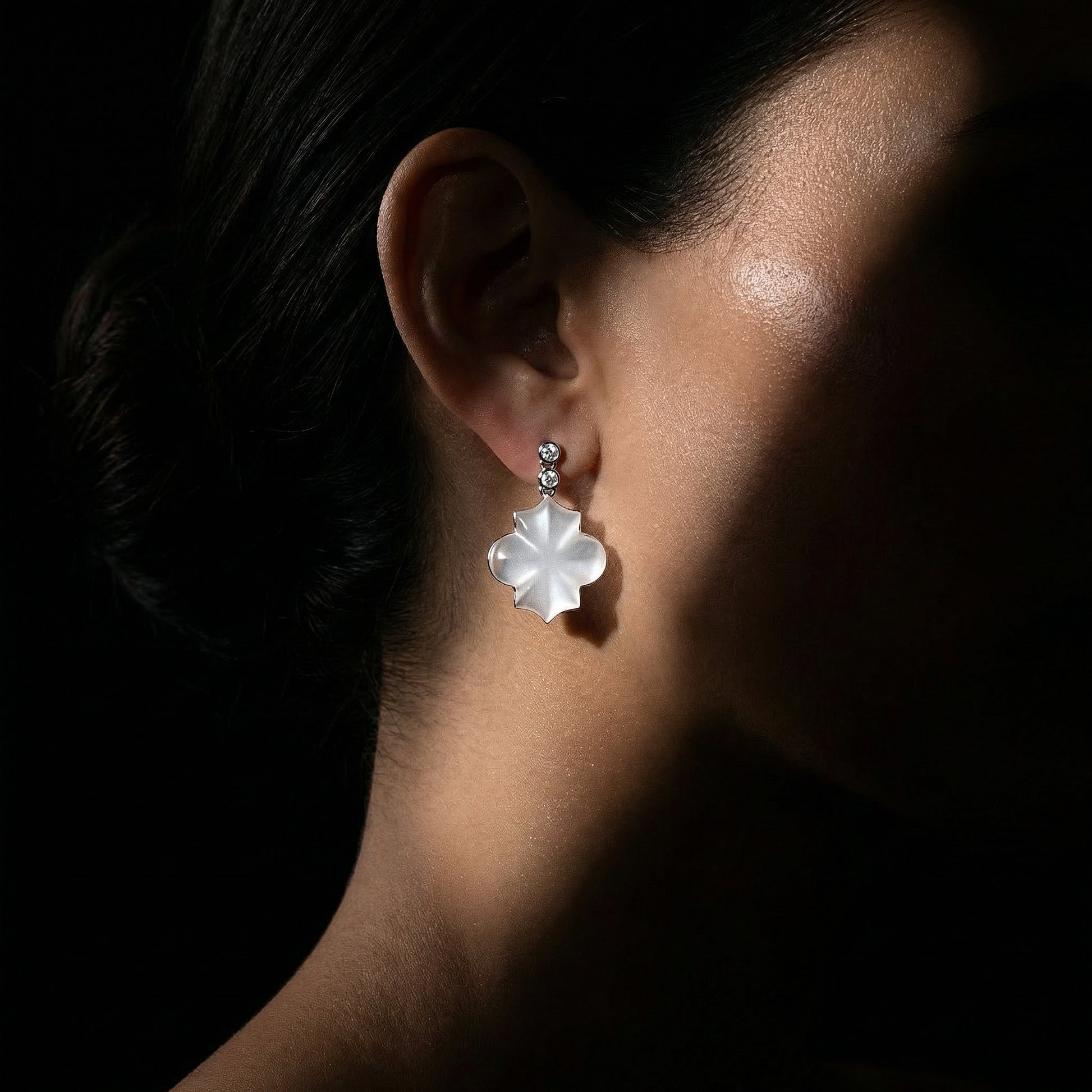 Close-up of an ear wearing a floral earring with a dark background