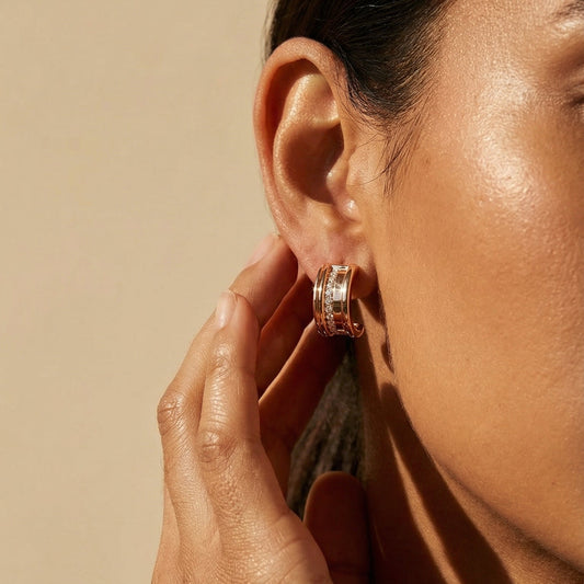 Close-up of a person wearing hoop earrings with a neutral background