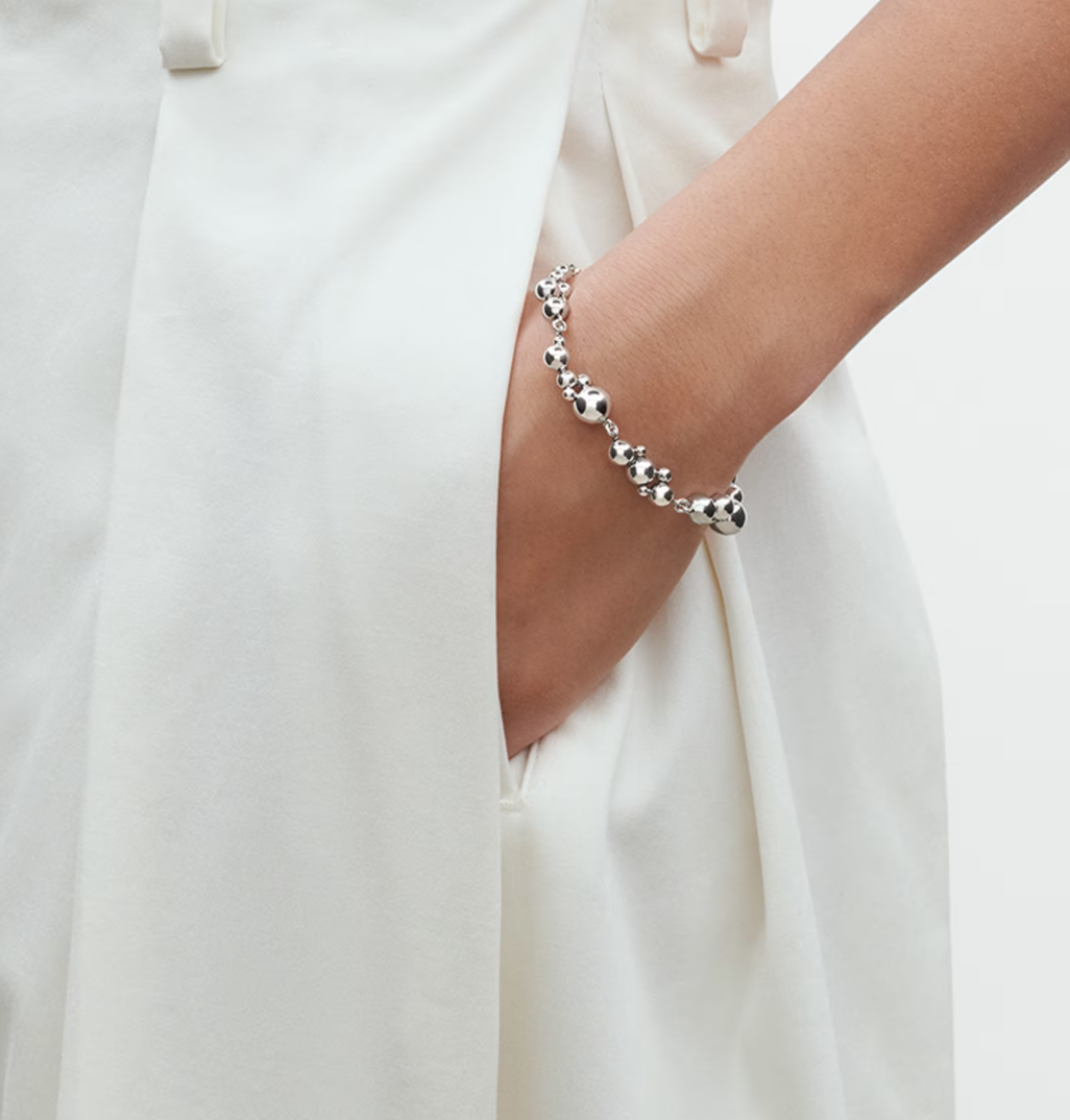 Silver bracelet on a person's wrist with a white background