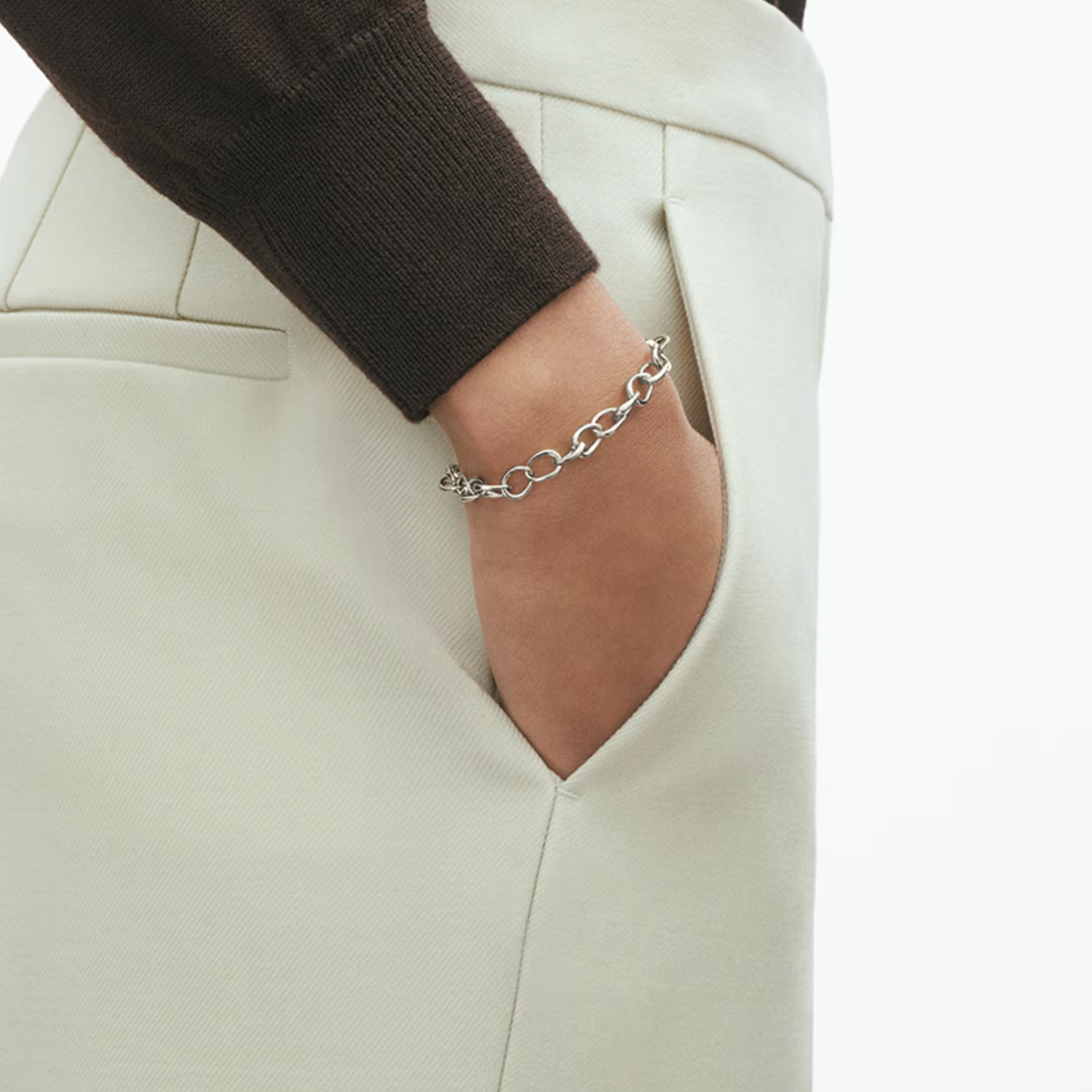 Person wearing a silver bracelet on a plain background