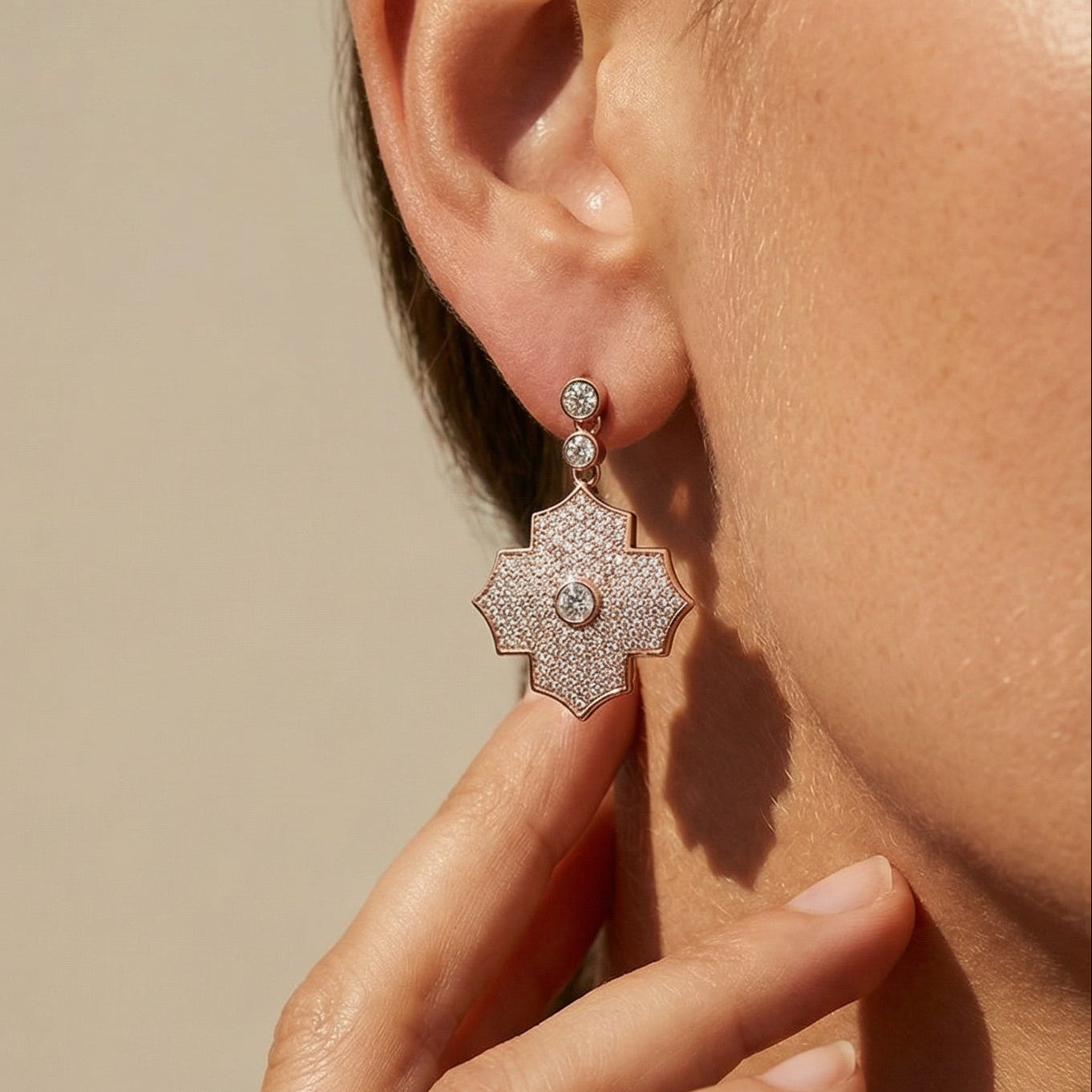 Close-up of a person wearing a silver earring with a beige background