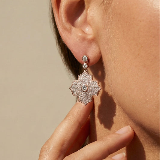 Close-up of a person wearing a silver earring with a beige background
