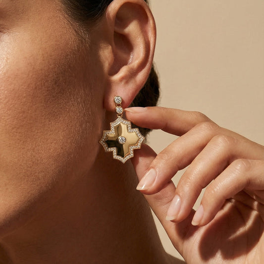 Close-up of a person wearing a gold earring with a beige background
