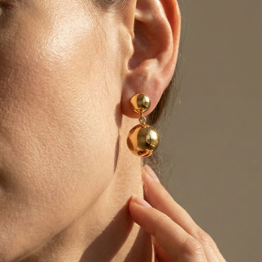 yellow gold two bead drop earrings worn by a model 