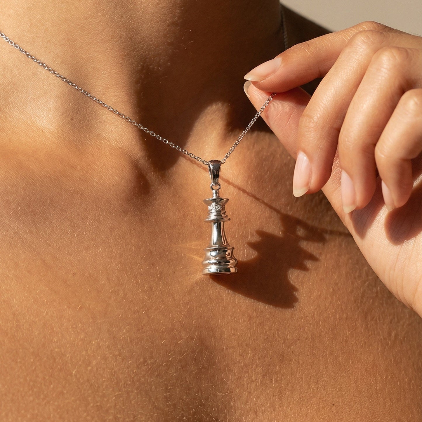 white gold white diamond chess queen necklace on a model 