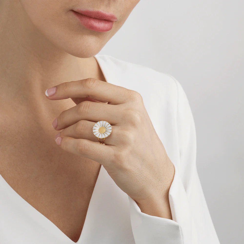 Close-up of a hand wearing a floral ring with a plain background