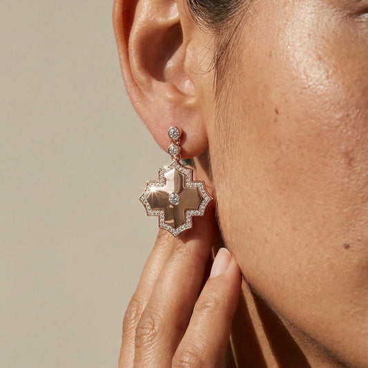 Close-up of a person wearing a decorative earring with a neutral background