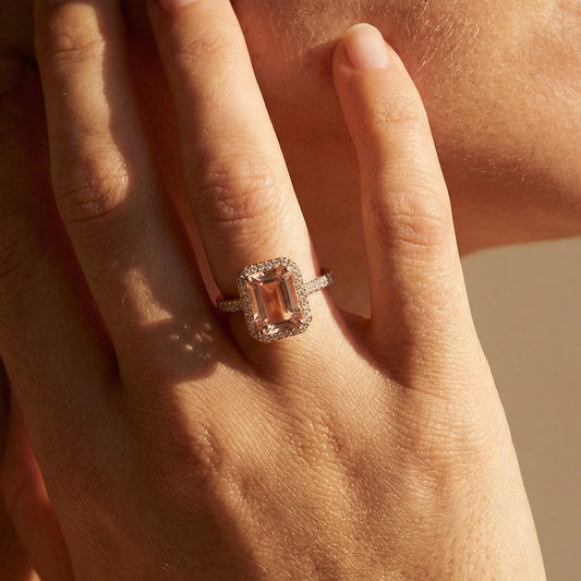 Close-up of a hand wearing a ring with a large gemstone, touching the face.