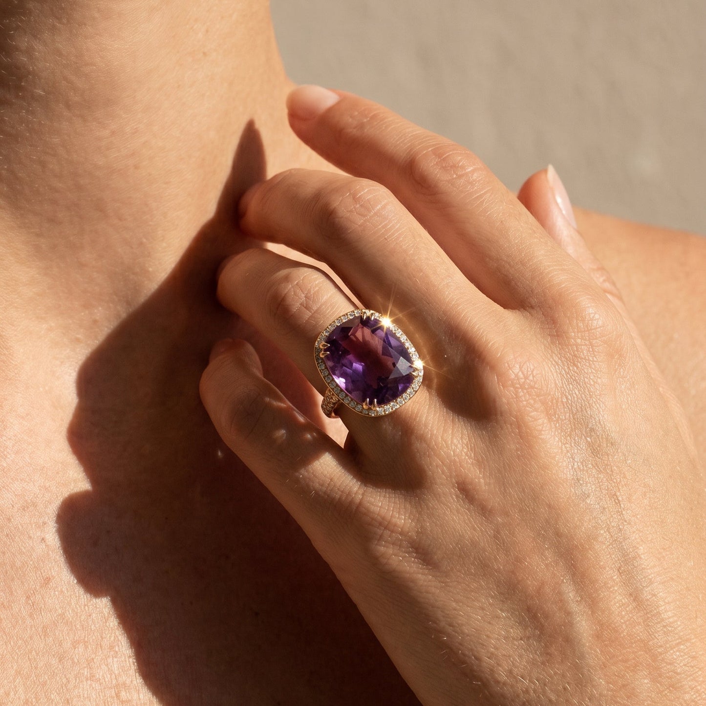 Peter Ungar Amethyst yellow gold ring with white diamonds worn by a model on a  neutral background 
