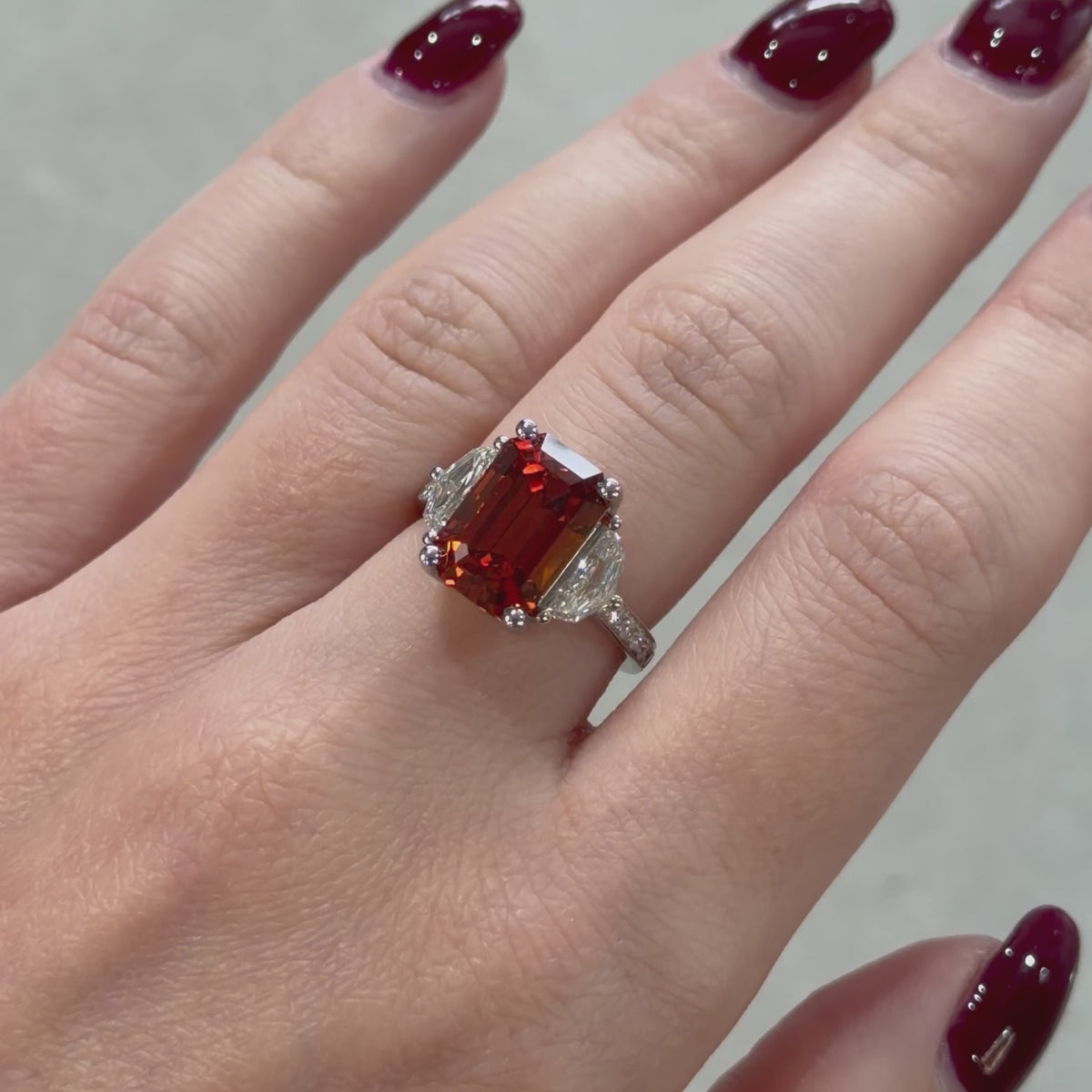 Mandarin Garnet platinum and diamond ring being presented on a hand 