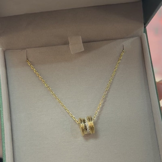 A video of a yellow gold white diamond small single bead rondel necklace in a branded box 
